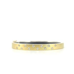 DESCRIPTION 6MM. Silver hinged bangle featuring an 18k gold push button style clasp and a solid 18k gold sheet top set with 12 white diamonds 0.60ct total combined diamond weight.